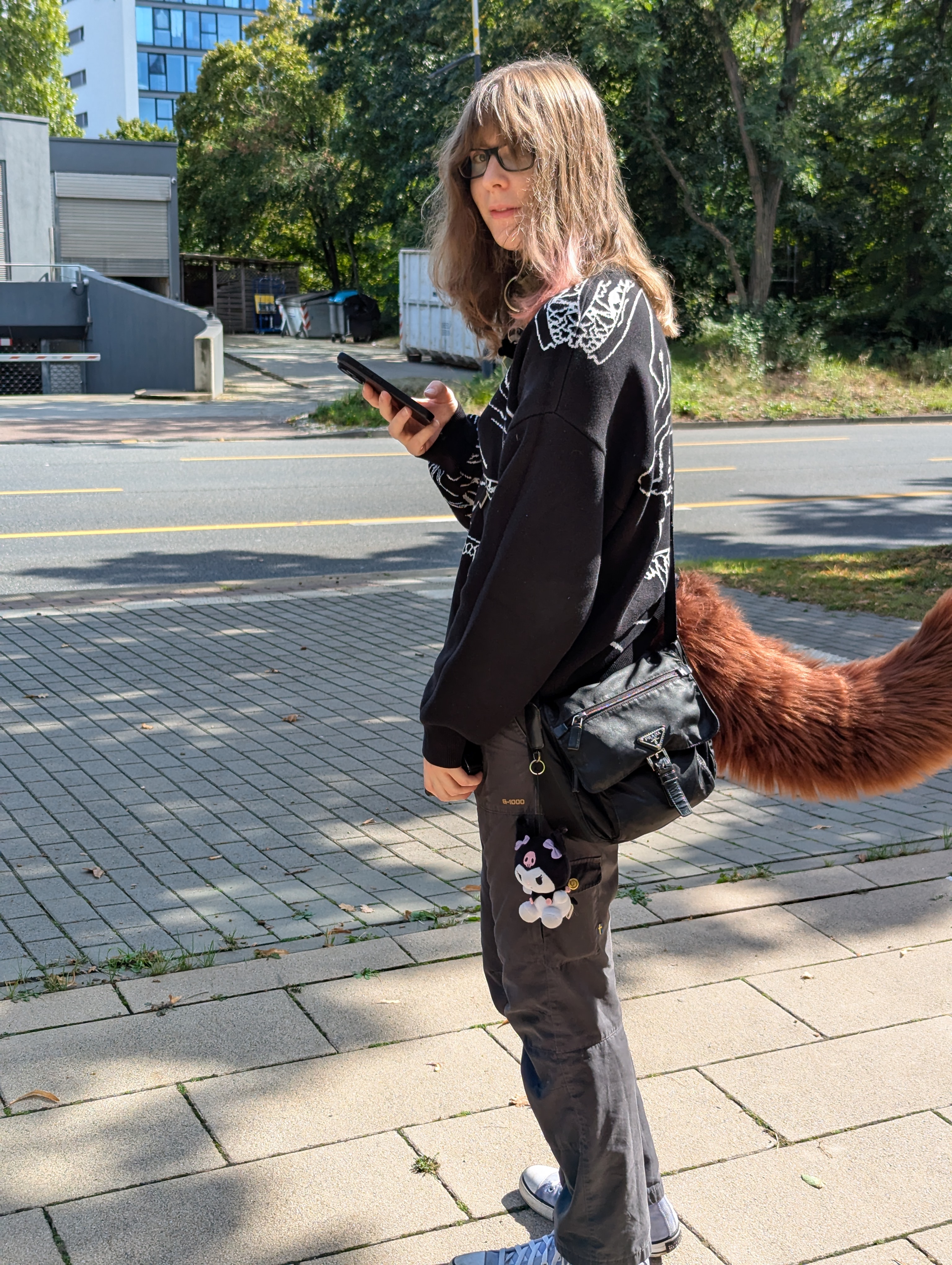 picture of me standing on a sidewalk. i look a little confused and im wearing a fluffy tail